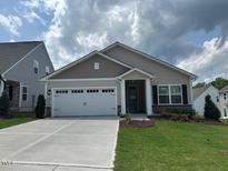 Charming single-story home featuring a two-car garage, manicured lawn, and neutral siding with stone accents at 206 Jetson Creek Way, Youngsville, NC 27596