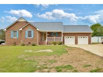 Charming single-story brick home featuring a manicured front lawn and attached garage at 6042 Elliott Bridge Rd, Linden, NC 28356