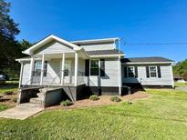 Charming exterior of a two-story home with a well-manicured lawn, inviting front porch, and beautiful landscaping at 668 Surl Mount Tirzah Rd, Timberlake, NC 27583
