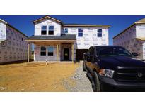 New construction featuring Tyvek wrap, situated on a lot with fresh gravel and a black truck parked nearby at 677 White Birch Ln, Angier, NC 27501