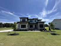 Beautiful two-story home with a well-manicured lawn and stone accents under a clear blue sky at 200 Broadleaf Ln, Youngsville, NC 27596