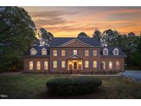 Stately brick home featuring symmetrical design, dormer windows, shutters, and professional landscaping at sunset at 2238 Lakeview Ter, Burlington, NC 27215
