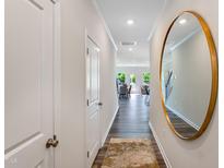 Inviting hallway with hardwood floors, white trim, and a decorative round mirror leading to the living area at 244 Paramount Dr # 24, Smithfield, NC 27577