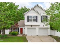 Charming two-story home featuring a bright red door, a two car garage and complemented by mature trees and landscaping at 104 Harvolly Dr, Holly Springs, NC 27540