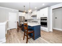 Bright kitchen with a blue island, stainless steel appliances and white cabinets at 10530 Sablewood Dr # 112, Raleigh, NC 27617