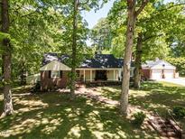 Charming brick home with a welcoming front porch nestled among mature trees and lush greenery at 107 Forest Rd, Oxford, NC 27565