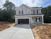 Two-story home with gray siding, black shutters, an attached garage, and a concrete driveway at 169 Pecan Valley Way, Four Oaks, NC 27524