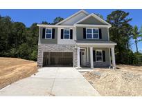 Charming two-story home with stone accents, green siding, and an attached two-car garage at 183 Pecan Valley Way, Four Oaks, NC 27524