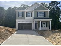 Two-story home featuring an open garage, green siding, a covered porch, and a new concrete driveway at 183 Pecan Valley Way, Four Oaks, NC 27524