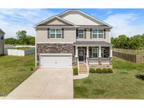 Charming two-story home boasts a stone facade, inviting front porch, and a well-manicured lawn at 2415 Ivy Knoll Dr, Mebane, NC 27302