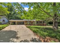 Charming brick home with a covered carport, lush trees and a wooden wheelchair ramp leading to the front door at 424 Raleigh View Rd, Raleigh, NC 27610