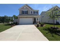 Charming two-story home featuring a two-car garage, stone accents, and a well-manicured front lawn at 521 Morning Light Dr, Angier, NC 27501