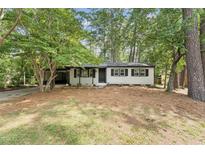 Charming single-story home featuring classic curb appeal with black accents and mature trees in the front yard at 620 Wexford Dr, Raleigh, NC 27603