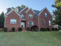Charming two-story brick home with mature landscaping and a well-manicured front lawn at 1003 Red Sunset Dr, Apex, NC 27502