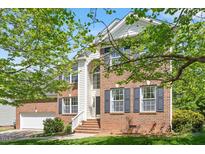 Charming two-story brick home with an attached garage, landscaped yard, and classic architectural details at 1007 Grandover Dr, Durham, NC 27713
