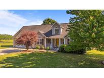 Charming home featuring manicured lawn, mature trees, and a welcoming front porch with a bright yellow door at 106 Contender Dr, Clayton, NC 27520