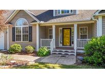 Inviting front porch with white railing, columns, and a vibrant yellow front door at 106 Contender Dr, Clayton, NC 27520