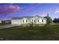 Charming single-story home featuring a well-manicured lawn, an attached garage and an American flag at 182 Jesse Dr, Smithfield, NC 27577