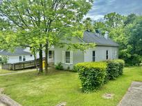 Charming home featuring gray siding, a lush green lawn, mature trees and manicured shrubbery at 211 Webb St, Roxboro, NC 27573