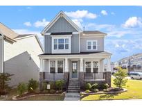 Charming two-story home featuring a welcoming front porch with stone accents and beautifully landscaped yard at 2919 Winter Crop Way, Apex, NC 27502