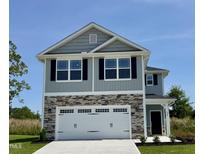 Two-story home featuring a stone-accented facade, attached garage, and manicured landscaping at 332 Bishop Ln, Sanford, NC 27330