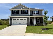 Two-story home featuring gray siding, a stone garage, and a well-manicured lawn at 356 Bishop Ln, Sanford, NC 27330