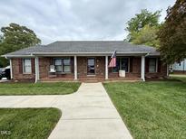 Charming brick home with a covered front porch, tidy landscaping, and an American flag at 3605 Mine Creek Rd, Burlington, NC 27217