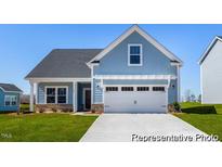 Charming blue home featuring a two-car garage, front porch, and well-manicured front lawn at 517 W Brocklyn St # 63P, Benson, NC 27504