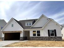 Charming new construction home featuring a stone base, white siding, and an attached two car garage at 1306 Cricket St, Elon, NC 27244