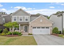 Charming two-story home with brick accents, manicured lawn, and a welcoming front porch with seating at 2650 Turner Pines Dr, New Hill, NC 27562