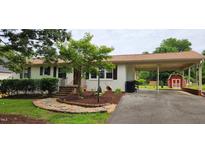 Charming single story home with white painted brick, a covered parking area and a red storage shed at 2917 Trail Six, Burlington, NC 27215