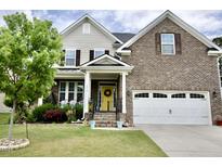 Charming two-story home with brick and siding, complemented by a well-manicured lawn and inviting front door at 3032 Curling Creek Dr, Apex, NC 27502