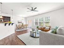 Inviting living room featuring wood floors, ceiling fan, and a dining area with large windows for abundant natural light at 525 Durants Neck Ln, Morrisville, NC 27560