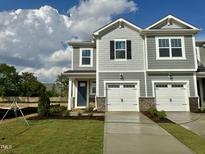 Charming townhome featuring a one-car garage, gray siding, and lovely landscaping on a well-maintained green lawn at 58 Twin Birch Dr, Angier, NC 27501