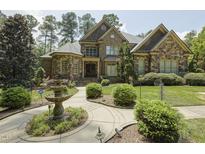 Stunning stone home featuring lush landscaping, a charming fountain, and a curved walkway leading to the entrance at 5901 Charleycote Dr, Raleigh, NC 27614