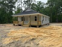Charming single-story home featuring a welcoming front porch and light gray siding, nestled in a wooded setting at 604 Natchez Trace, Fuquay Varina, NC 27526