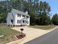Charming two-story home with a classic white exterior, black shutters, and a spacious driveway at 607 Wahlbrink Dr, Wake Forest, NC 27587