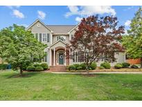 Charming two-story home with a manicured lawn, mature trees, and a welcoming brick entrance at 608 Driftwood Dr, Gibsonville, NC 27249