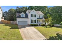Charming two-story home featuring a long driveway, attached garage, manicured lawn, and welcoming front porch at 612 Lakeview Ave, Wake Forest, NC 27587