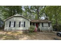 Charming single-story home featuring light green siding, brick foundation, and classic black shutters, framed by mature trees at 7312 Ray Rd, Raleigh, NC 27613