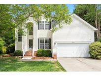 Charming two-story home with white siding, black shutters, landscaped yard, and attached two-car garage at 8814 Waynick Dr, Raleigh, NC 27617