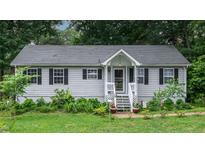 Charming single story home with gray siding, black shutters and inviting front porch with pretty landscaping at 106 Palomino Cv, Louisburg, NC 27549