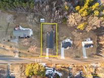 An aerial view of a single story home with a dark roof, driveway, and bordered by trees at 1101 Ridge Rd, Roxboro, NC 27573