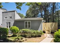 Inviting gray home featuring a cozy front yard with lush green bushes and a charming wooden fence at 112 Carmichael Ct, Cary, NC 27511