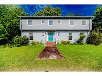 Charming home with a brick walkway, light grey facade, and a vibrant turquoise front door at 1706 Carthage St, Sanford, NC 27330