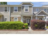 Inviting townhome with stone accents, manicured landscaping, and a cozy front porch at 2207 Bankshill Row, Raleigh, NC 27614