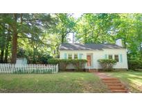 Charming white home featuring blue shutters, brick steps, and a quaint white picket fence at 409 Green St, Sanford, NC 27330