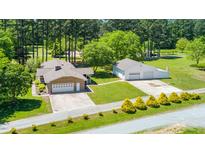 A beautiful brick home features a detached garage, a well-manicured lawn, and mature trees at 4418 Carpenter Pond Rd, Durham, NC 27703