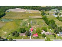 Expansive aerial view of a property featuring lush fields, a pond, and several well-maintained houses with vibrant green surroundings at 5423 Nc-39, Selma, NC 27576