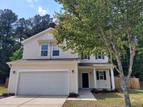Charming two-story home with vinyl siding, attached two-car garage, and a tree in the front yard at 7 Mint Hill Ct, Durham, NC 27703